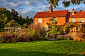 RYE HALL FARM, YORKSHIRE - DESIGNER SARAH MURCH - COUNTRY GARDEN WITH LATE SUMMER / AUTUMN GRASSES AND PERENNIALS. LAWN, ORNATE METAL GAZEBO, GARDEN ORNAMENT, HOUSE, OCTOBER