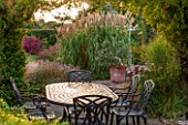 RYE HALL FARM, YORKSHIRE - DESIGNER SARAH MURCH - COUNTRY GARDEN IN AUTUMN, OCTOBER - PERGOLA WITH PATIO, METAL TABLE AND CHAIRS, A PLACE TO SIT, EATING, DINING