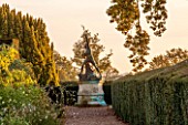 HOLE PARK, KENT: VIEW ALONG GRAVEL PATH TO STATUE OF EAGLE SLAYER - DAWN, WALLED GARDEN, COUNTRY GARDEN, CLASSIC, FALL, AUTUMN, OCTOBER