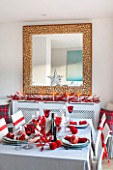 SALTWATER, NORFOLK : DESIGNER KAREN MOORE - CHRISTMAS, DECEMBER, WINTER - THE DINING ROOM IN RED AND WHITE - TABLE, CHAIRS, RIBBON, DECORATION, LIGHTS, CANDLES, DINNER, CORK MIRROR