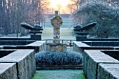 GREAT FOSTERS. SURREY: THE FORMAL GARDEN WITH CLIPPED TOPIARY SHAPES IN YEW. WINTER, CLASSIC COUNTRY GARDEN, JANUARY, FROST, FROSTY, FROSTED, DAWN, LAWN