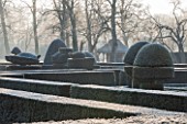GREAT FOSTERS. SURREY: THE FORMAL GARDEN WITH CLIPPED TOPIARY SHAPES IN YEW. WINTER, CLASSIC COUNTRY GARDEN, JANUARY, FROST, FROSTY, FROSTED, DAWN, LAWN
