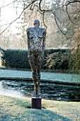 GREAT FOSTERS. SURREY: SOARING FIGURE - SCULPTURE IN STAINLESS STEEL BY RICK KIRBY BESIDE THE MOAT - WATER, ART, CLASSIC, FORMAL, COUNTRY GARDEN, WINTER, FROST, JANUARY
