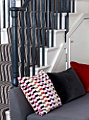 SALLY STOREY HOUSE, LONDON: OPEN PLAN SITTING ROOM / HALL WITH GREY CHAIR WITH CUSHIONS - BLACK AND WHITE STAIRCASE, STAIRS