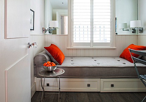SALLY_STOREY_HOUSE_LONDON_BEDROOM_IN_WHITE_AND_ORANGE_WITH_ORANGE_CUSHIONS_AND_STORAGE_UNITS_BENEATH