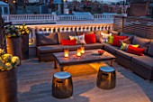 SALLY STOREY HOUSE, LONDON: ROOF TERRACE / GARDEN - WOODEN TABLE, CANDLES, SEATING WITH CUSHIONS - LIT UP AT NIGHT, LIGHTS, LIGHTING, CONTAINERS WITH HYDRANGEAS