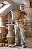 WHICHFORD POTTERY, WARWICKSHIRE: ADAM KEELING HOLDING NEWLY HANDMADE TERRACOTTA CONTAINER IN THE WORKSHOP