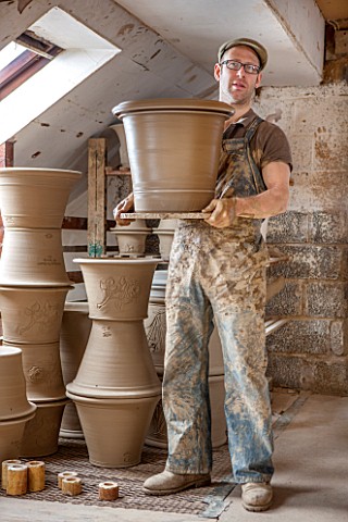 WHICHFORD_POTTERY_WARWICKSHIRE_ADAM_KEELING_HOLDING_NEWLY_HANDMADE_TERRACOTTA_CONTAINER_IN_THE_WORKS