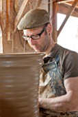 WHICHFORD POTTERY, WARWICKSHIRE: ADAM KEELING THROWING A NEWLY HANDMADE TERRACOTTA CONTAINER IN THE WORKSHOP