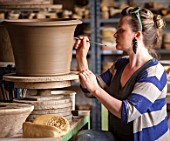 WHICHFORD POTTERY, WARWICKSHIRE: POTTER SAS COOPER FETTLING A TERRACOTTA CONTAINER IN THE WORKSHOP