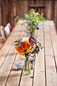 WHICHFORD POTTERY, WARWICKSHIRE: THE CAFE - WOODEN TABLE AND CHAIRS WITH GLASS VASES FILLED WITH FLOWERS - ORANGE TULIP IN THE FRONT GLASS JAR