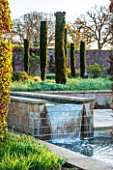 BROUGHTON GRANGE, OXFORDSHIRE: DESIGNER TOM STUART-SMITH - POOL AND WATERFALL IN THE WALLED GARDEN WITH GREENHOUSE BEHIND - SPRING, WATER, STEPPING STONES, RILL, CANAL