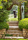 LA JEG, PROVENCE, FRANCE: DESIGNER ANTHONY PAUL - STONE STEPS AND DOORWAY WITH VIEW TO SCULPTURE LOVERS BY MARZIA COLONNA. SPRING. MEDITERRANEAN, GARDEN, GREEN, PROVENCE, MAY
