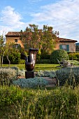JEG, PROVENCE, FRANCE: DESIGN: ANTHONY PAUL - THE HOUSE WITH BLUE SHUTTERS. CLIPPED PLANTS BESIDE LAWN, SCULPTURE LOVERS BY MARZIA COLONNA. SUMMER,  COUNTRY, GARDEN