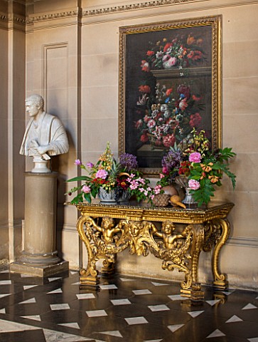 CHATSWORTH_HOUSE_DERBYSHIRE_FLORABUNDANCE__THE_PAINTED_HALL_GILDED_TABLE_WITH_FLORAL_ARRANGEMENTS_AN