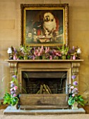 CHATSWORTH HOUSE,DERBYSHIRE:FLORABUNDANCE-THE NORTH ENTRANCE;FIREPLACE.SUMMER FLOWERS PICKED FROM THE GARDEN IN PURPLE/PINK.JARS OF LUPINS,ASTRANTIA,CAMPANULA,DIGITALIS,MINT,MILLET