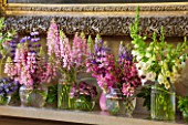 CHATSWORTH HOUSE,DERBYSHIRE:FLORABUNDANCE-THE NORTH ENTRANCE;SHELF-SUMMER FLOWERS PICKED FROM THE GARDEN IN PURPLE/PINK. JARS OF LUPINS,ASTRANTIA,CAMPANULA,DIGITALIS,MINT,MILLET