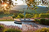 LA JEG, PROVENCE, FRANCE: DESIGNER ANTHONY PAUL - LAVENDER - LAVENDULA GROSSO - BESIDE STONE TERRACE AND SWIMMING POOL WITH SCULPTURE AND MONT VENTOUX. SUNRISE, SUMMER, JUNE