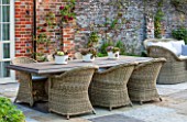 THE COACH HOUSE, SURREY: OUTDOOR PATIO AND DINING AREA WITH LARGE TABLE AND WICKER CHAIRS. SEMPERVIVUMS IN POTS ON TABLE. A PLACE TO SIT. ENTERTAIN, SUMMER, GARDEN