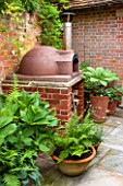 THE COACH HOUSE, SURREY: BBQ/BRICK BARBEQUE/CHIMINEA,OUTDOOR COOKING AREA WITH VARIOUS FERMS AND RODGERSIAS IN POTS ON STONE PATIO.SHADE,SHADY.