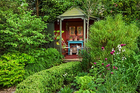 THE_LODGE_BURFORD_OXFORDSHIRE_TEA_HOUSE_IN_LUSH_GREEN_GARDEN_PLANTED_WITH_BOX_YEW_HEBE_HAKONECHLOA_M