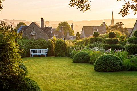GREYHOUNDS_BURFORD_OXFORDSHIRETHE_MAIN_BORDERS_AND_LAWN_IN_DAWN_LIGHTFRAMED_BY_YEW_TOPIARY_HORNBEAM_