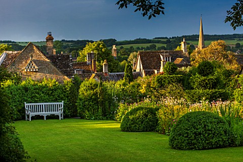 GREYHOUNDS_BURFORD_OXFORDSHIRE_COTTAGE_STYLE_LAWN_AND_BORDER_WITH_WOODEN_BENCH_IN_BORDER_IS_SELINUM_