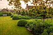 GREYHOUNDS, BURFORD, OXFORDSHIRE: CLASSIC COUNTRY GARDEN WITH LAWN, BOX DOMES AND YEW TOPIARY. BORDERS WITH COTTAGE GARDEN PLANTS. BENCHES. A PLACE TO SIT. SUMMER