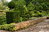 OXLEAZE FARM, OXFORDSHIRE: EDGE OF TERRACE AND LOW STONE WALL WITH YEW AND BOX TOPIARY. BUXUS, TAXUS BACCATA, SHAPED, CLIPPED, SHAPES, EVERGREEN, FOLIAGE, SUMMER,