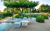 PRIVATE GARDEN, GLOUCESTERSHIRE DESIGNED BY MARCUS BARNETT: TABLES, CHAIRS, CLIPPED TOPIARY DOMES, GRAVEL, TERRACE, RILL, WATER, SUMMER, GARDEN, COTSWOLDS