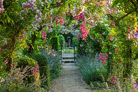 EASTLEACH_HOUSE_GLOUCESTERSHIRE_WALLED_GARDEN_GRAVEL_PATH_WITH_ARCH_NEPETA_SIX_HILLS_GIANT_ROSA_PRIN