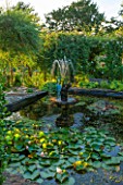 EASTLEACH HOUSE, GLOUCESTERSHIRE:LILY POND, CHERUB FOUNTAIN, BRONZE HERON SCULPTURE, EVENING LIGHT. COUNTRY GARDEN, ENGLISH, WATER, POOL, POND