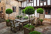 CALENDARS:BURFORD,OXFORDSHIRE:COURTYARD GARDEN WITH OUTDOOR DINING AREA.STONE PAVERS, TABLE & CHAIRS WITH POTTED BAY TREES UNDERPLANTED WITH CAMPANULA. AGAPANTHUS IN POT. SUMMER.