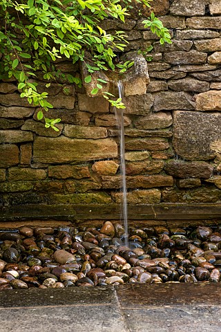 CALENDARS_BURFORDOXFORDSHIRE_WATER_CASCADES_INTO_PEBBLE_POOL_FROM_MOUTH_OF_RILL_SET_INTO_DRY_STONE_W