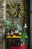 ABIGAIL AHERN HOUSE, LONDON: THE DINING ROOM - DARK, INTERIOR, WALL, BERRY WREATH, DECORATION, STAGHORN PLANT, DRINKS TABLE