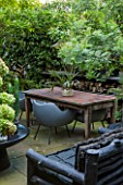 ABIGAIL AHERN HOUSE, LONDON: GARDEN, PATIO WITH TABLE, CHAIRS, FAUX STAGHORN PLANT IN CONTAINER, OUTDOOR KITCHEN