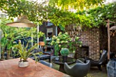 ABIGAIL AHERN HOUSE, LONDON: TOWN GARDEN WITH TABLE, CHAIRS, LIGHT, FIREPLACE, FAUX CACTUS