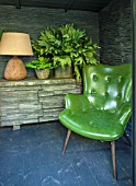ABIGAIL AHERN HOUSE, LONDON: TOWN GARDEN. INTERIOR OF CABIN TYPE SHED. LAMP, GREEN CHAIR, SEAT, FAUX PLANTS IN CONTAINERS, FAUX SLATED WALL, DAWLISH SIDEBOARD WITH STONE FACADE