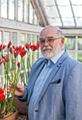 GUERNSEY NERINE FESTIVAL: NERINE EXPERT ANDREW LANOE WITH NERINE SARNIENSIS IN THE LOWER GLASSHOUSE, CANDIE GARDENS. GUERNSEY LILY