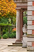 MORTON HALL, WORCESTERSHIRE: DETAIL OF SANDSTONE COLUMNS AND LIDDED URNS WITH BOX BALLS AND TREE IN AUTUMN COLOUR