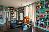 MORTON HALL, WORCESTERSHIRE: LIBRARY WITH VIEWS OF SOUTH GARDEN.SHELVES BY WIENER WERKSTAETTEN,PAINTED IN FB DIX BLUE.CHERRY WOOD LECTERN.BLACK LEATHER RECAMIERE SOFAS