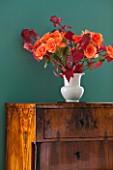 MORTON HALL, WORCESTERSHIRE: DINING ROOM. ANTIQUE CHEST OF DRAWERS WITH SMALL WHITE VASE WITH ORANGE ROSES AND FRESHLY PICKED AUTUMN MAPLE LEAF FOLIAGE