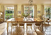 THE COACH HOUSE,SURREY:BREAKFAST ROOM WITH LARGE TABLE & CHAIRS, MANDARIN STONE FLOOR, FLOOR TO CEILING SASH WINDOWS AND DOORS TO PAVED PATIO.FRENCH COUNTRY STYLE, NEUTRAL DECOR