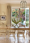 THE COACH HOUSE,SURREY:BREAKFAST ROOM WITH LARGE TABLE & CHAIRS, MANDARIN STONE FLOOR, DOORS TO PAVED PATIO.FRENCH COUNTRY STYLE, NEUTRAL DECOR