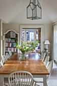 THE COACH HOUSE,SURREY:BREAKFAST ROOM WITH LARGE TABLE & CHAIRS, MANDARIN STONE FLOOR, BOOKCASE, GLASS & METAL CEILING LIGHT.FRENCH COUNTRY STYLE, NEUTRAL DECOR