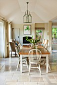 THE COACH HOUSE,SURREY:BREAKFAST ROOM WITH LARGE TABLE & CHAIRS,MANDARIN STONE FLOOR,BOOKCASE, METAL & GLASS CEILING LIGHT,WOOD BURNER.FRENCH COUNTRY STYLE, NEUTRAL DECOR