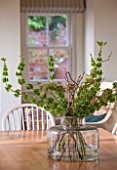 THE COACH HOUSE,SURREY: VASE OF FRESH FLOWERS/FOLIAGE ON WOODEN TABLE IN BREAKFAST ROOM