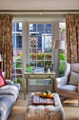 THE COACH HOUSE,SURREY: GARDEN ROOM WITH VIEW OF PATIO/LOGSTORE. SOFAS, CHAIR, SIDE TABLE, FABRIC FOOTSTOOL. COMFY, RELAXING, HOMELY, LIGHT, AIRY.