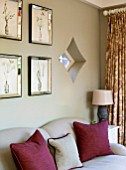 THE COACH HOUSE,SURREY: GARDEN ROOM WITH DETAIL OF NEUTRAL SOFA AND CLARET CUSHIONS. BOTANICAL PRINTS IN VENETIAN GLASS FRAMES ON WALL. DIAMOND SHAPED WINDOW