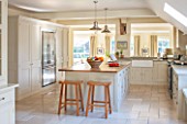 THE COACH HOUSE,SURREY:COUNTRY KITCHEN BY PLAIN ENGLISH, STOOLS FROM POTTERY BARN WITH BLUE LIMESTONE WORKTOPS.NEUTRAL DECOR,LIGHT,AIRY, TUMBLED MARBLE FLOOR, BELFAST/BUTLER SINK